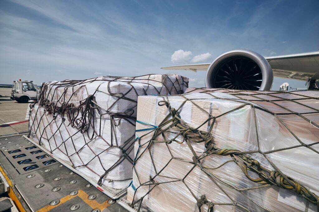 Air Cargo containers infront of jet engine of airplane - Air Freight
