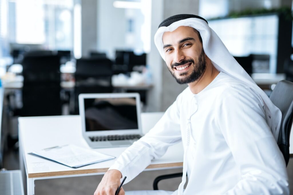 Handsome man with dish dasha working in an office of Dubai