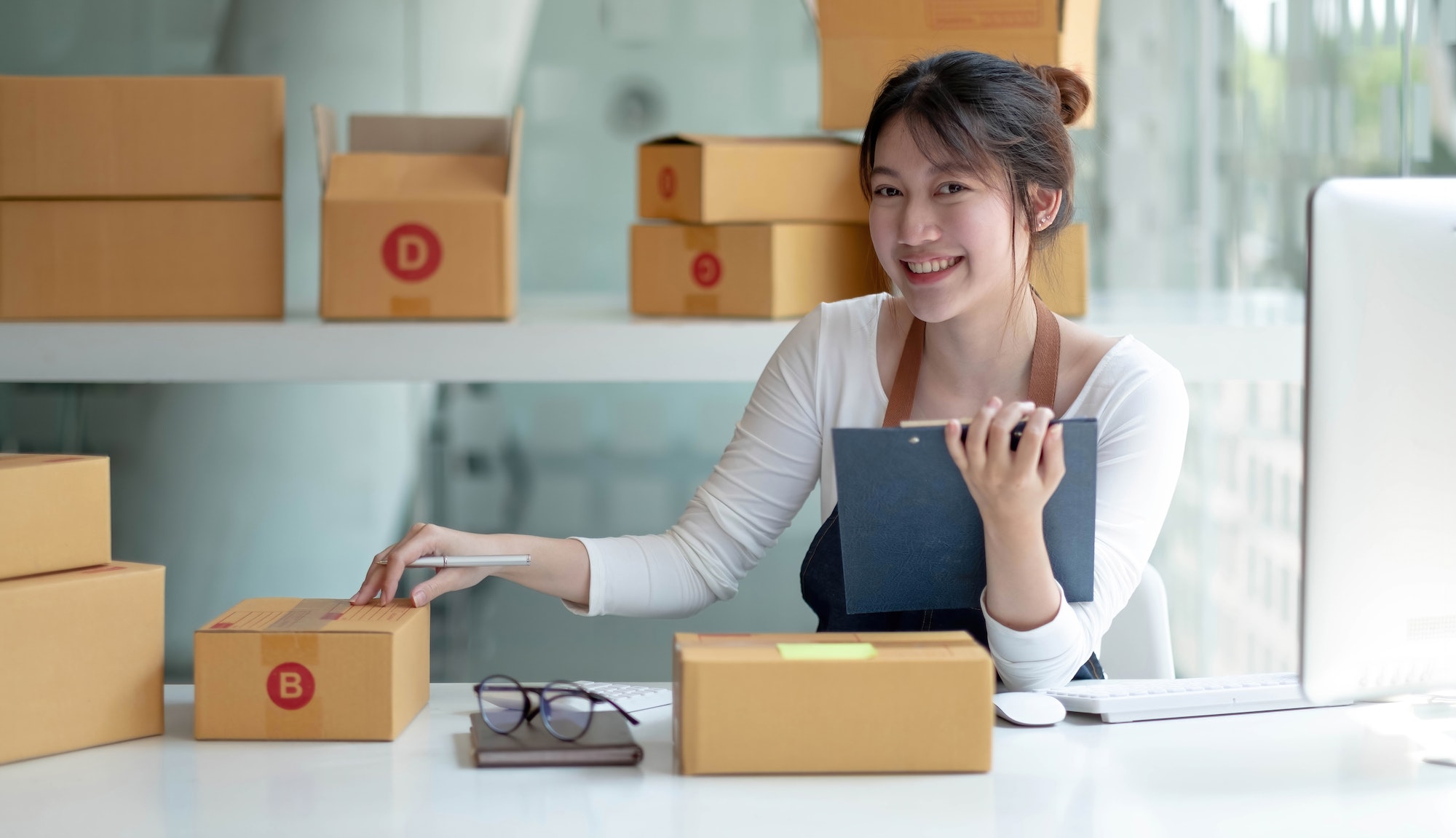 Portrait young asia female owner startup look at camera work happy with box at home prepare parcel